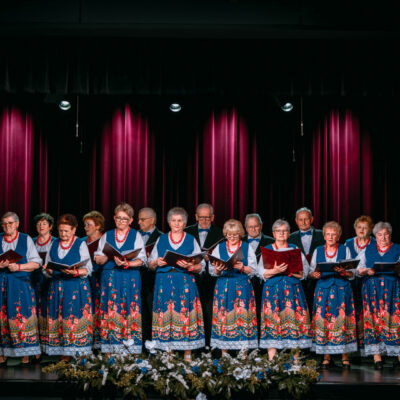 Członkowie chóru złota jesień prezentujący się na deskach sceny centrum kultury i sportu w grębocicach