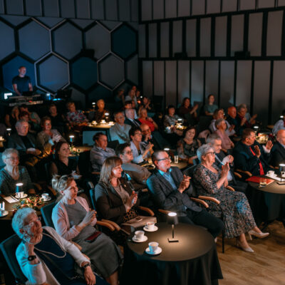 Pełna sala gości zaproszonych na okoliczność jubileuszu 20-lecia chóru złota jesień. Goście siedzą przy stolikach. Na stolikach znajdują się lampki.